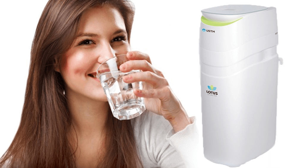 kobieta pijąca czystą wodę, a obok niej zmiękczacz wody